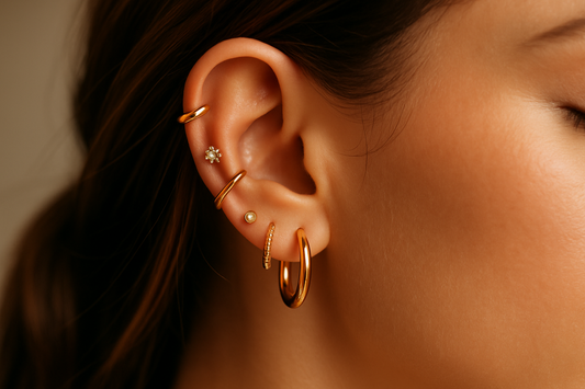 describe a ear's woman with a Collection of gold earrings including hoops, studs, and a close-up of an ear wearing multiple earrings.